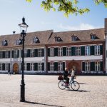 Weiter Platz mit alten herrschaftlichen haeusern und einer strassenlaterne und mann auf einem fahrrad im vordergrund