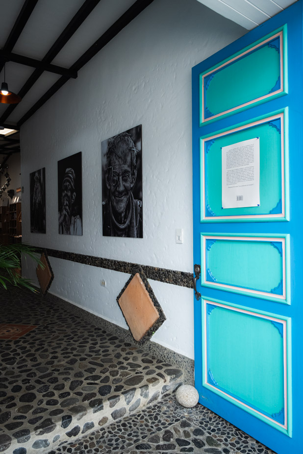 Türkise Holztür in einem traditionellen Haus in Jardín Kolumbien mit schwarz weiß Porträts an der Wand